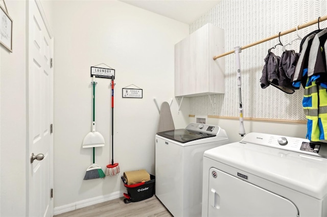 laundry area featuring independent washer and dryer, light wood finished floors, cabinet space, and baseboards