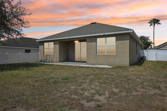 rear view of house featuring stucco siding, a gate, and a shingled roof