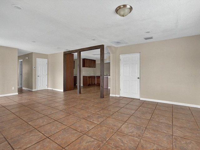 tiled empty room featuring baseboards