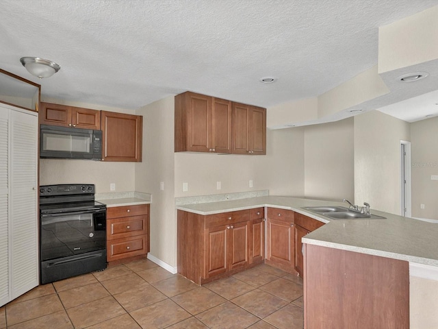 kitchen with black appliances, a peninsula, light tile patterned floors, a sink, and brown cabinets