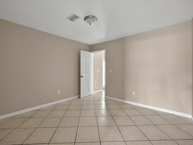 empty room featuring baseboards and light tile patterned floors