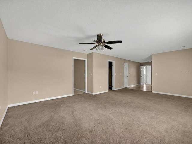 carpeted spare room with ceiling fan and baseboards