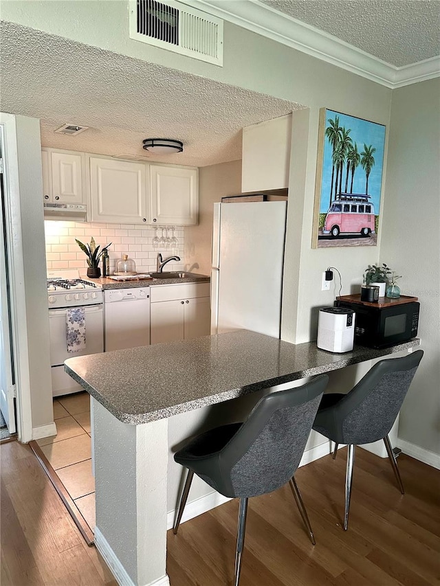 109 Oyster Bay Cir Unit 120, Altamonte Springs, FL 32701 - kitchen with white appliances, under cabinet range hood, light wood-type flooring, a textured ceiling, and white cabinetry