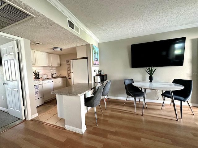 109 Oyster Bay Cir Unit 120, Altamonte Springs, FL 32701 - kitchen with white appliances, light wood-type flooring, white cabinetry, a textured ceiling, and a kitchen breakfast bar