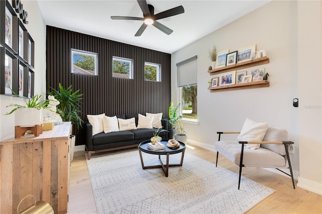 living area with light wood-style flooring, baseboards, and ceiling fan