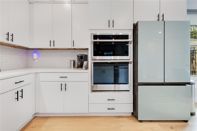 kitchen featuring freestanding refrigerator, decorative backsplash, light countertops, and light wood-type flooring