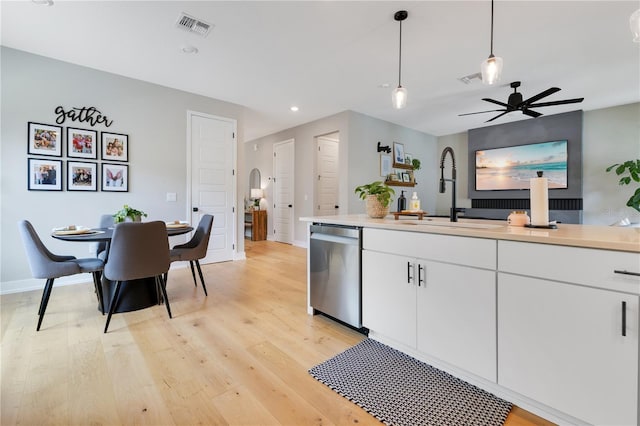 kitchen featuring stainless steel dishwasher, visible vents, a sink, white cabinetry, and light wood-style floors