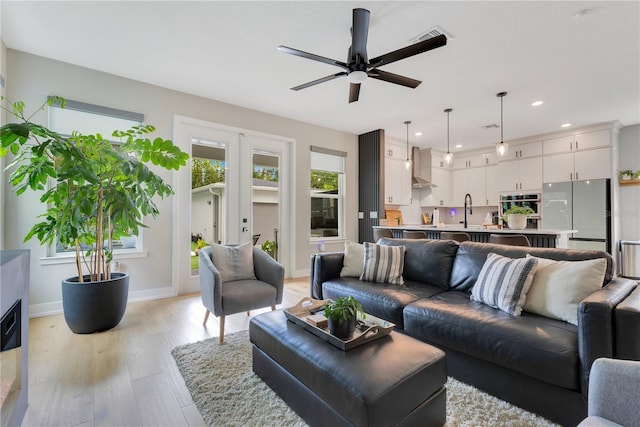 living area featuring a ceiling fan, light wood-style floors, recessed lighting, and baseboards