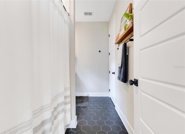 laundry area with dark tile patterned flooring, baseboards, and visible vents