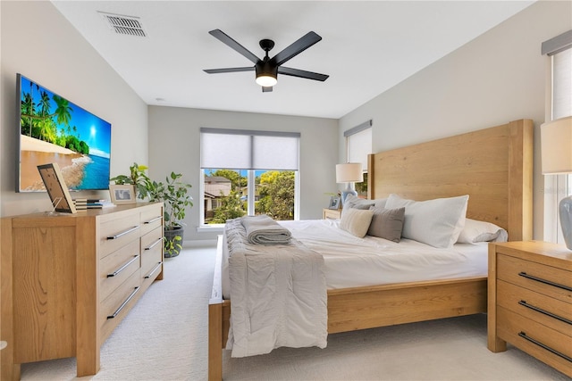 bedroom with light carpet, a ceiling fan, and visible vents