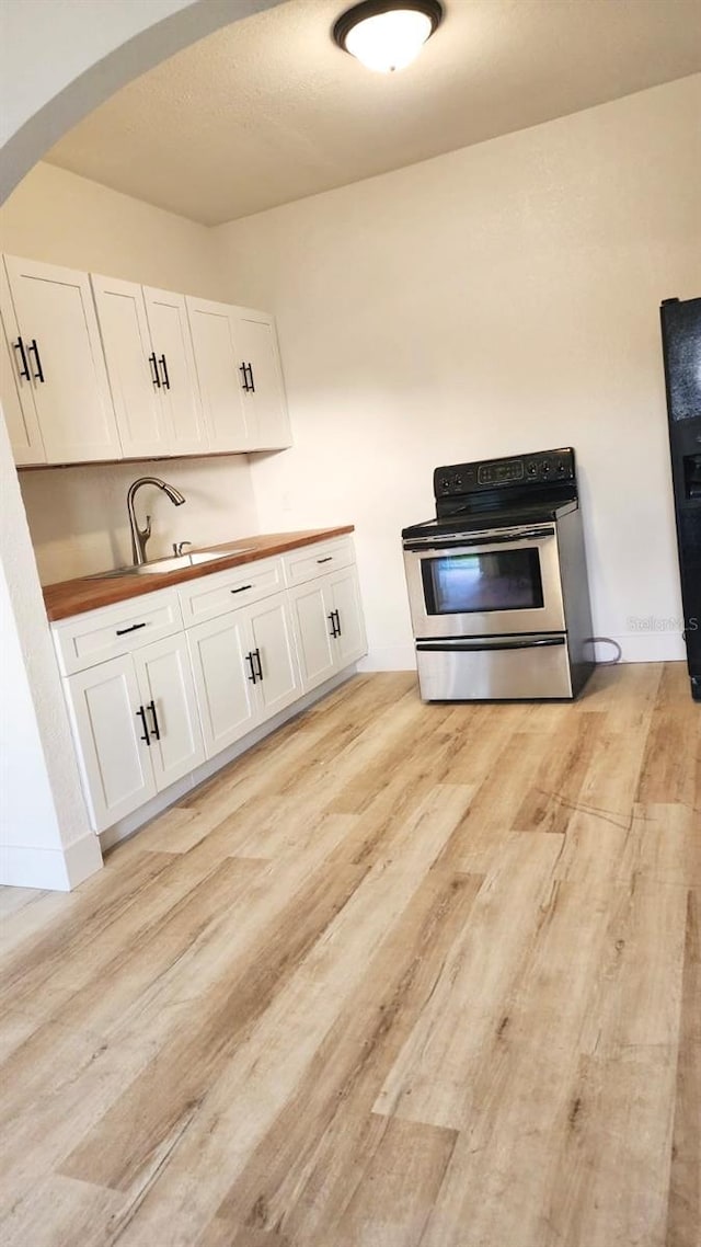 412 Bay St NW, Fort Meade, FL 33841 - kitchen featuring electric stove, light wood finished floors, white cabinetry, and wood counters