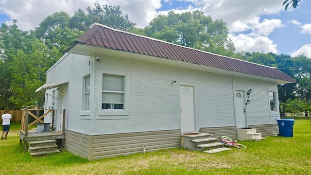 412 Bay St NW, Fort Meade, FL 33841 - rear view of property featuring entry steps, brick siding, a lawn, and metal roof