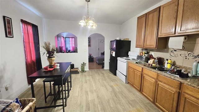 412 Bay St NW, Fort Meade, FL 33841 - kitchen with electric range, arched walkways, light wood finished floors, and brown cabinetry