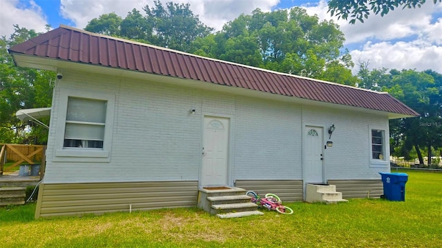 412 Bay St NW, Fort Meade, FL 33841 - back of property with entry steps, metal roof, a lawn, and brick siding