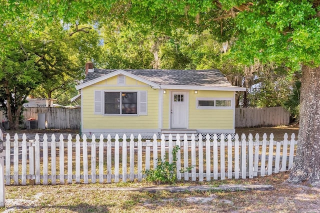 bungalow-style house with a chimney and a fenced front yard
