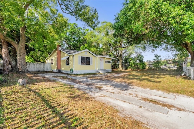 view of front of property featuring a chimney, driveway, a front lawn, and fence