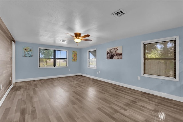 unfurnished room featuring ceiling fan, baseboards, visible vents, and wood finished floors