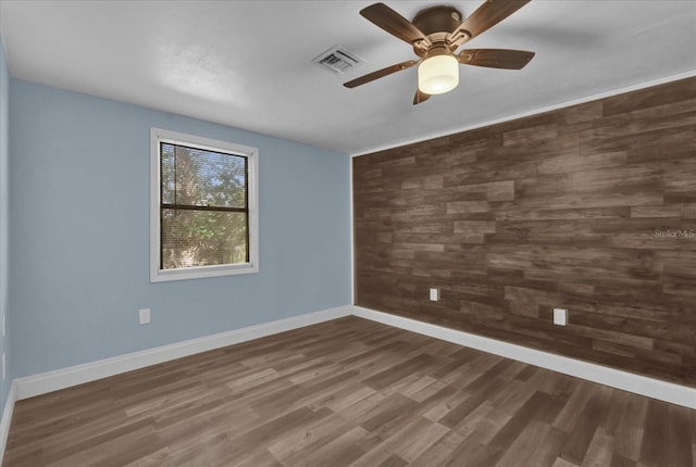 empty room featuring baseboards, a ceiling fan, visible vents, and wood finished floors