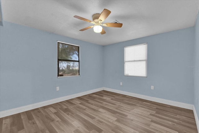 unfurnished room featuring a ceiling fan, plenty of natural light, wood finished floors, and baseboards