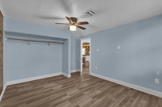 unfurnished bedroom with baseboards, a closet, visible vents, and wood finished floors