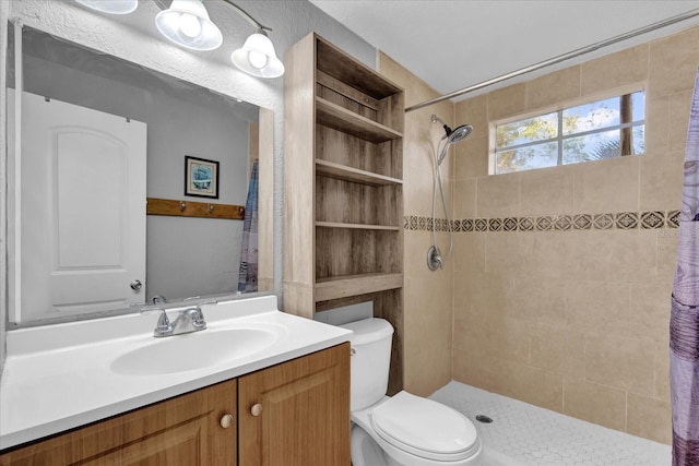 bathroom featuring vanity, toilet, and a tile shower