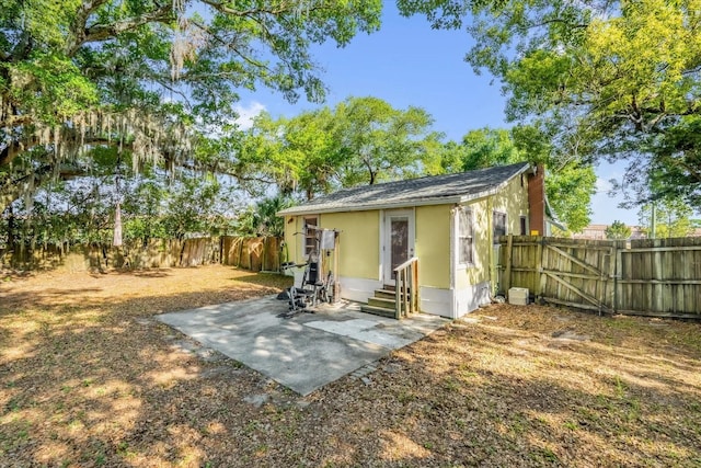 view of outbuilding with entry steps, a fenced backyard, and a gate
