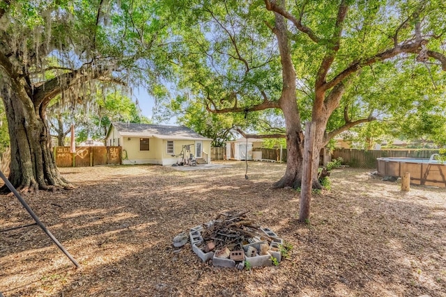 view of yard with an outdoor fire pit, an outdoor structure, a shed, and a fenced backyard