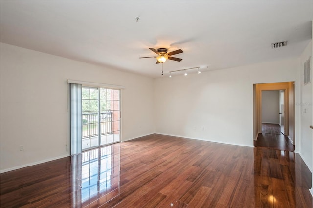 empty room featuring rail lighting, dark wood-style flooring, baseboards, and ceiling fan