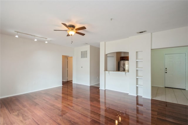 unfurnished living room with ceiling fan, arched walkways, visible vents, and wood finished floors