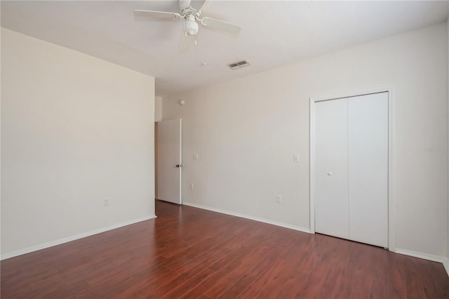 unfurnished bedroom with a closet, wood finished floors, visible vents, a ceiling fan, and baseboards