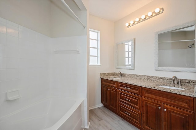 bathroom featuring a sink, double vanity, tub / shower combination, and wood finished floors