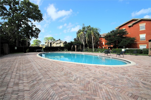 community pool with a patio and fence