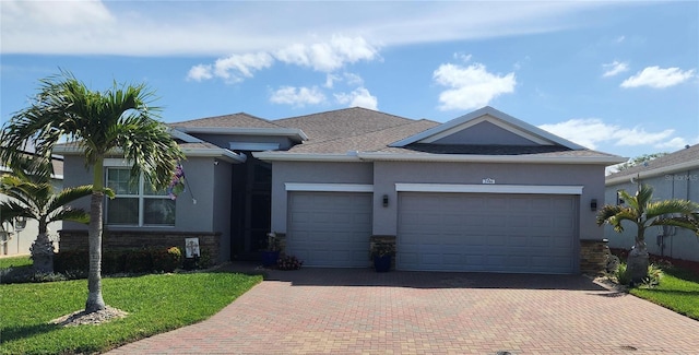 ranch-style house featuring decorative driveway, an attached garage, stucco siding, stone siding, and a front lawn