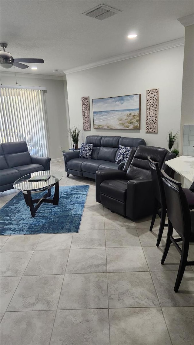 tiled living area featuring ceiling fan, visible vents, and crown molding