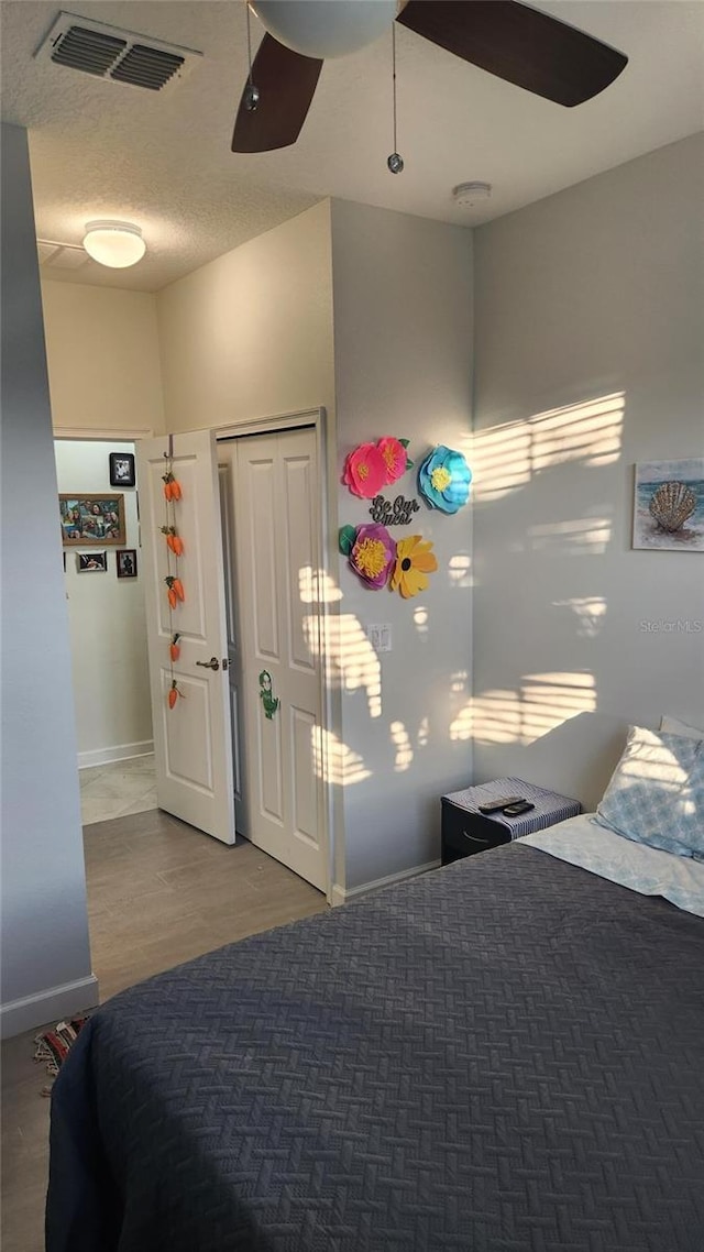 bedroom with wood finished floors, visible vents, baseboards, and a ceiling fan