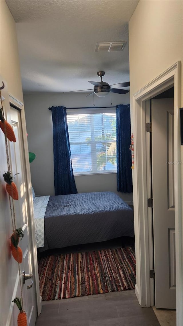bedroom featuring a ceiling fan, visible vents, and wood finished floors