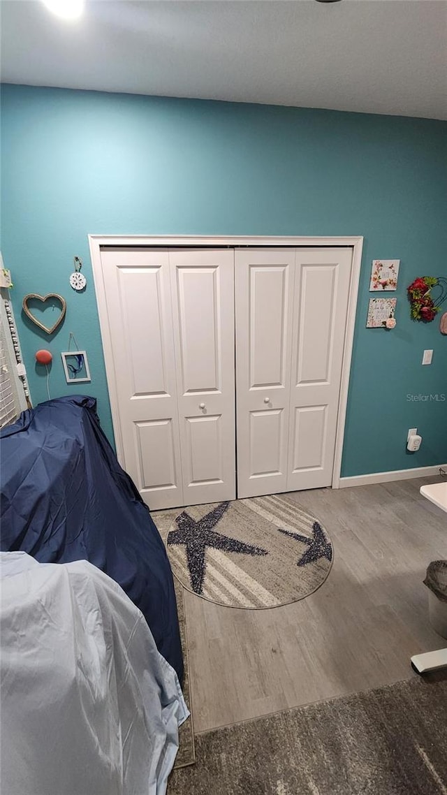 bedroom featuring baseboards, a closet, and wood finished floors