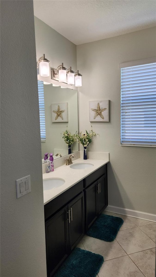 bathroom featuring a sink, tile patterned flooring, double vanity, and baseboards