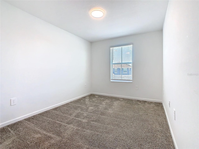 spare room featuring carpet flooring and baseboards