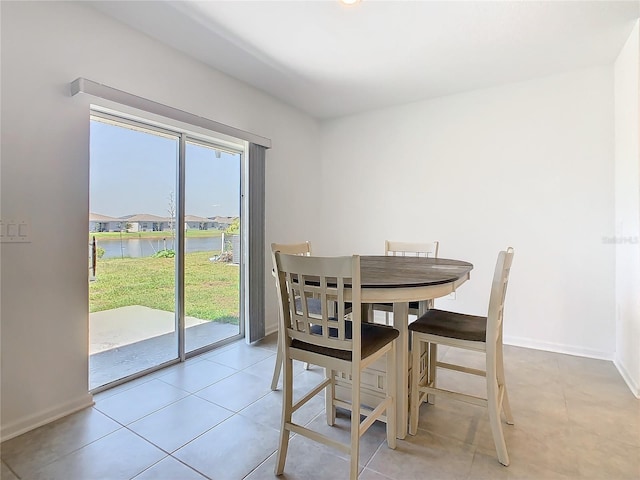 dining area featuring a water view, healthy amount of natural light, baseboards, and light tile patterned floors