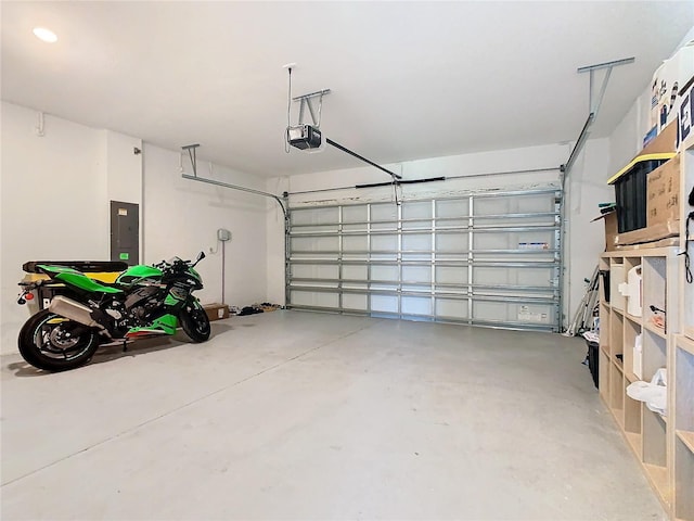garage featuring a garage door opener, electric panel, and recessed lighting