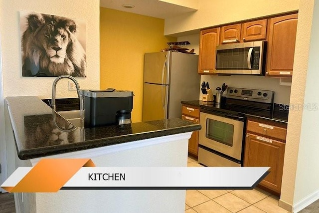 8101 Resort Village Dr Unit 31501, Orlando, FL 32821 - kitchen with light tile patterned flooring, a peninsula, brown cabinets, dark countertops, and stainless steel appliances