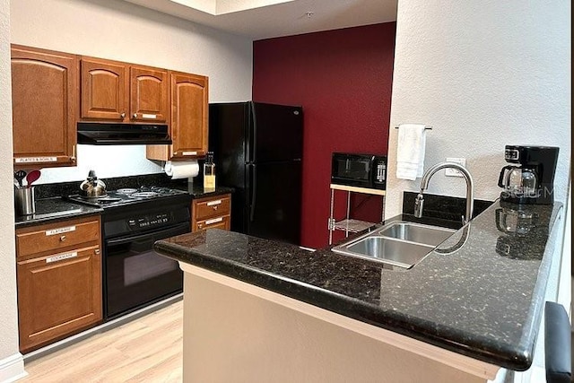 8125 Resort Village Dr Unit 51201, Orlando, FL 32821 - kitchen featuring a peninsula, light wood-style flooring, a sink, black appliances, and under cabinet range hood