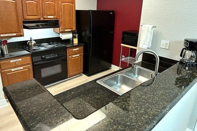 8125 Resort Village Dr Unit 51201, Orlando, FL 32821 - kitchen with brown cabinets, a sink, extractor fan, black appliances, and a textured wall