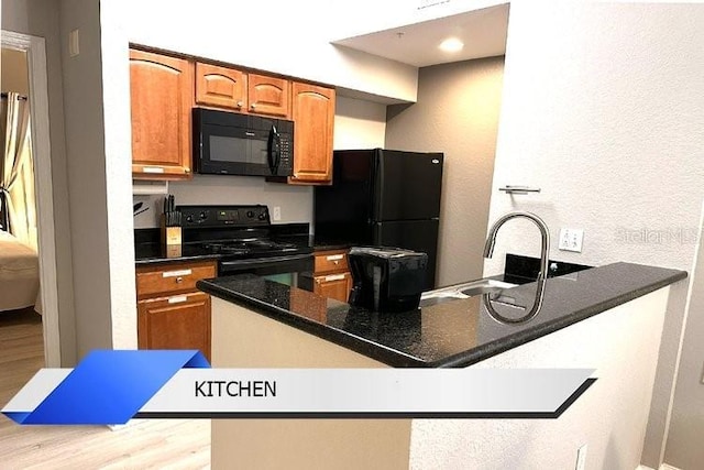 8112 Poinciana Blvd Unit 1502, Orlando, FL 32821 - kitchen featuring a peninsula, brown cabinets, a sink, black appliances, and light wood-style floors
