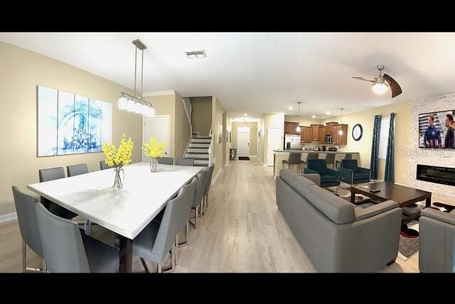 1466 Moon Valley Dr, Champions Gate, FL 33896 - living area with a ceiling fan, light wood-style flooring, a stone fireplace, visible vents, and stairs