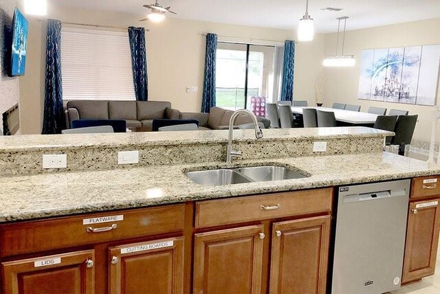 1466 Moon Valley Dr, Champions Gate, FL 33896 - kitchen with stainless steel dishwasher, brown cabinets, open floor plan, and a sink