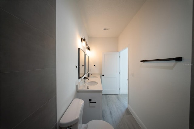 16600 SW 23rd Avenue Rd, Ocala, FL 34473 - bathroom featuring double vanity, toilet, wood finished floors, visible vents, and baseboards