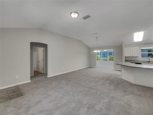 2708 La Posada Dr, The Villages, FL 32162 - unfurnished living room with light colored carpet, visible vents, a sink, and vaulted ceiling