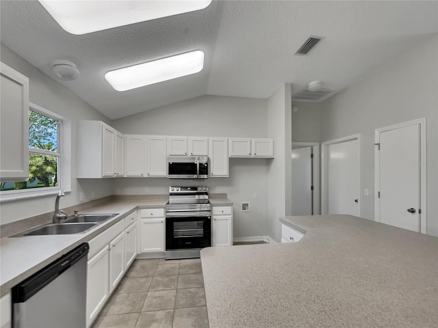 2708 La Posada Dr, The Villages, FL 32162 - kitchen with lofted ceiling, visible vents, a sink, white cabinetry, and appliances with stainless steel finishes